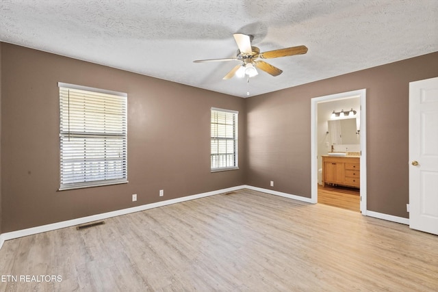 338 Lindsey Mill Cir, Rocky Top, TN 37769 - unfurnished bedroom featuring light wood-type flooring, baseboards, a textured ceiling, ensuite bathroom, and ceiling fan