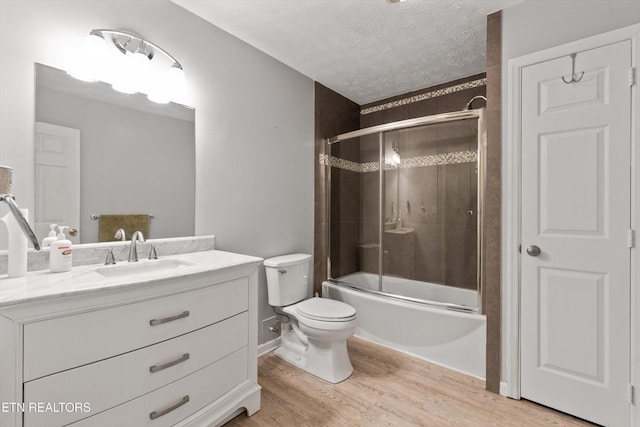 338 Lindsey Mill Cir, Rocky Top, TN 37769 - bathroom with a textured ceiling, wood finished floors, vanity, toilet, and bath / shower combo with glass door