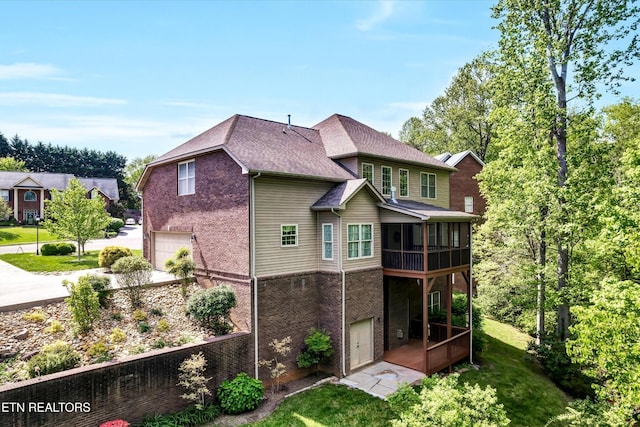 5606 Bridgehampton Dr, Powell, TN 37849 - rear view of house with an attached garage, brick siding, a shingled roof, a sunroom, and a lawn