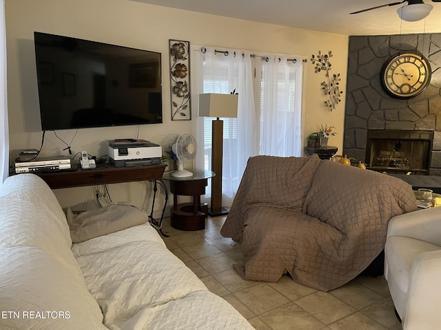tiled living room featuring a fireplace and a ceiling fan