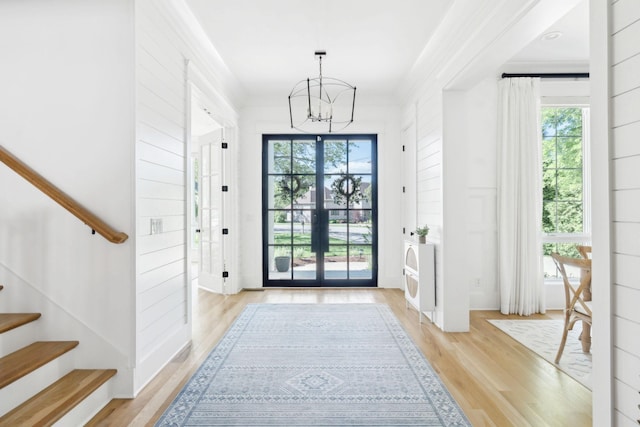 entryway featuring a chandelier, stairway, light wood finished floors, and plenty of natural light