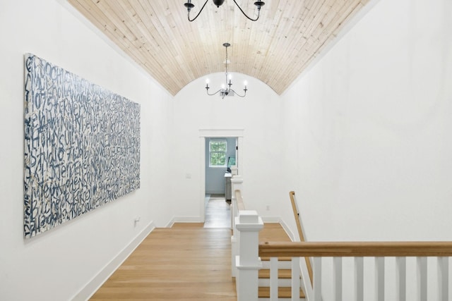 hallway featuring a chandelier, lofted ceiling, light wood-type flooring, an upstairs landing, and baseboards