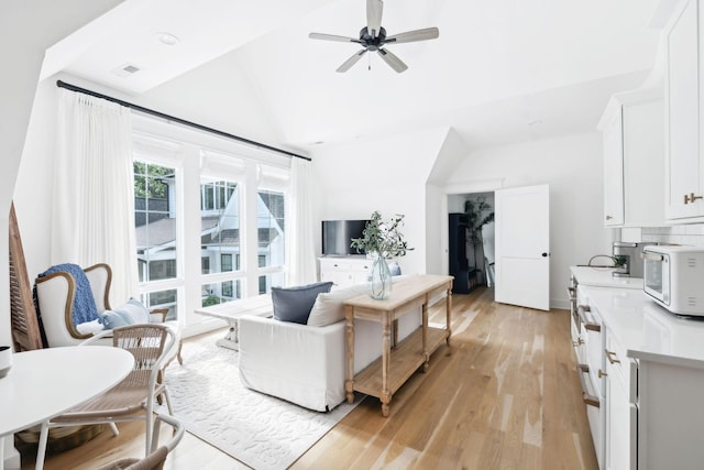 living area featuring vaulted ceiling, ceiling fan, and light wood-style flooring