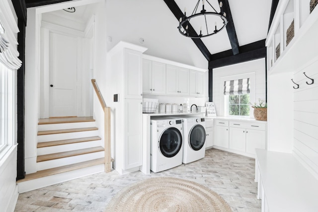 washroom featuring washing machine and clothes dryer, a chandelier, a towering ceiling, and cabinet space