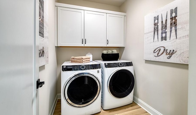 washroom featuring cabinet space, washer and dryer, baseboards, and light wood-style flooring