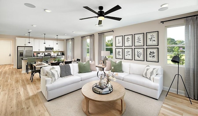 living room with light wood-style floors, baseboards, recessed lighting, and a ceiling fan