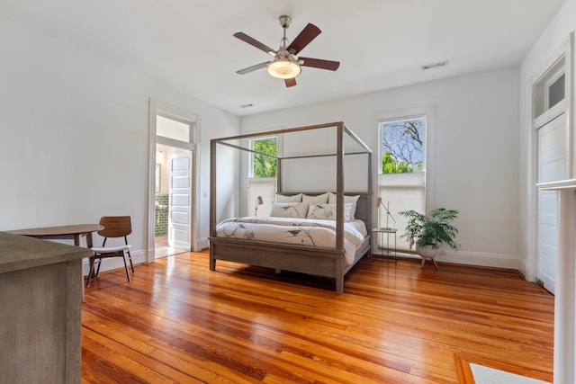 bedroom with multiple windows, light wood-style flooring, baseboards, and ceiling fan