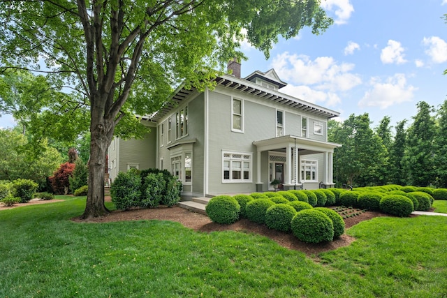 view of side of home featuring a chimney and a lawn