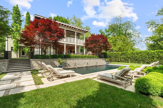 back of property with a balcony, a patio, a yard, and stairway