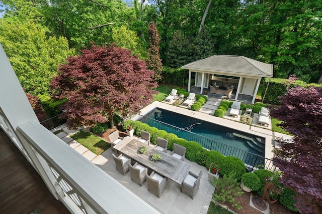 view of pool featuring an exterior structure, an outbuilding, a patio area, fence, and outdoor dining area