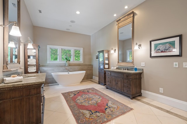 bathroom featuring tile patterned floors, a soaking tub, two vanities, baseboards, and recessed lighting