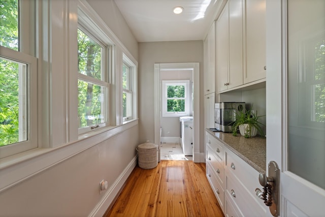 doorway to outside featuring baseboards, light wood-style floors, and washer / dryer