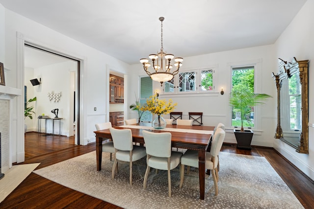 dining area with a chandelier, dark wood-style floors, a tile fireplace, and baseboards