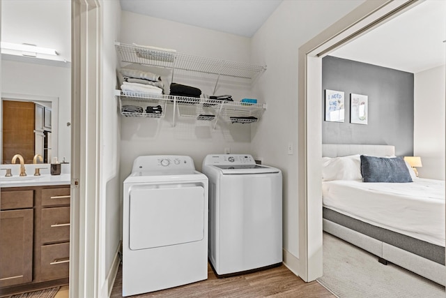 clothes washing area with light wood-type flooring, independent washer and dryer, and baseboards