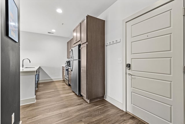 kitchen with stainless steel appliances, wood finished floors, recessed lighting, baseboards, and a sink