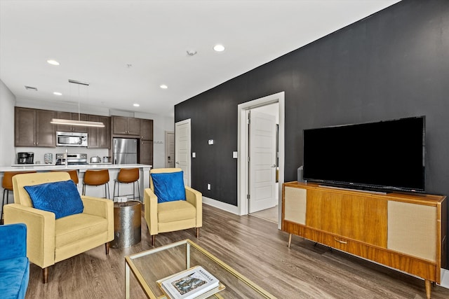 living area with wood finished floors, recessed lighting, and baseboards
