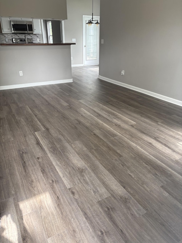 2642 Sewanee Pl, Murfreesboro, TN 37128 - unfurnished living room with dark wood-type flooring, baseboards, a chandelier, and healthy amount of natural light