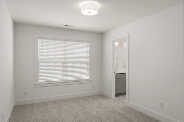 spare room with light colored carpet and baseboards