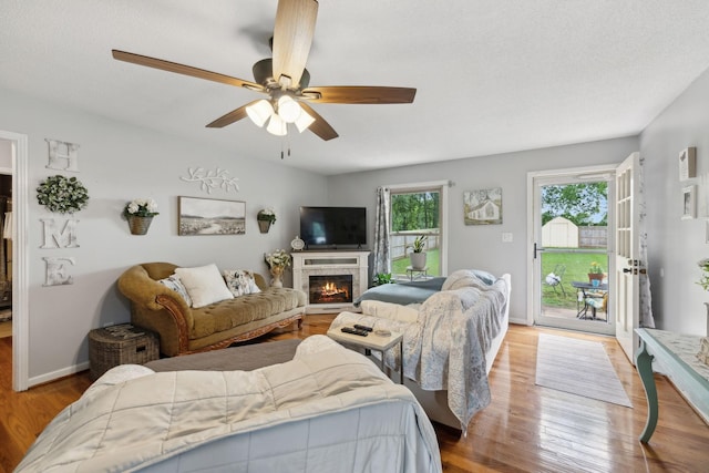 405 Mockingbird Dr, Mount Pleasant, TN 38474 - living area featuring wood finished floors, a ceiling fan, a warm lit fireplace, and baseboards