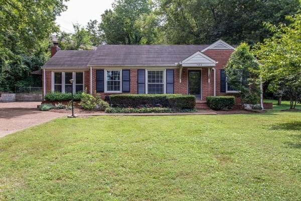 ranch-style home featuring a front yard, brick siding, and a chimney