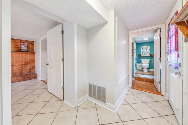 2046 Scribners Mill Rd, Culleoka, TN 38451 - corridor featuring a textured ceiling, brick wall, light tile patterned floors, and baseboards