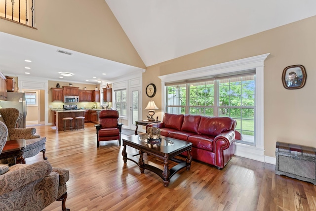 living area with healthy amount of natural light, light wood-style flooring, baseboards, recessed lighting, and high vaulted ceiling
