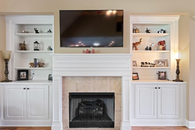 living area featuring a tiled fireplace and built in shelves