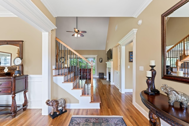 entrance foyer featuring stairs, ceiling fan, wood finished floors, a fireplace, and crown molding