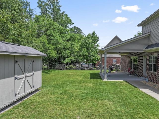 view of grassy yard with a patio, a shed, an outbuilding, and ceiling fan