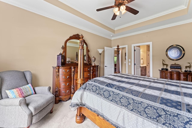 bedroom featuring a tray ceiling, carpet floors, crown molding, connected bathroom, and ceiling fan