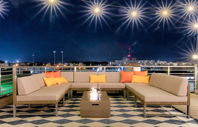 patio at night with outdoor lounge area and a balcony