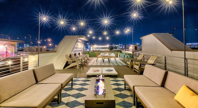 patio at night with an outdoor living space with a fire pit