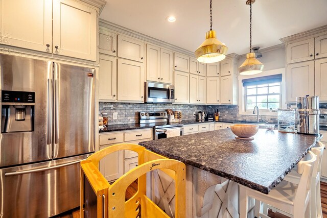 82 Staggs Rd, Ethridge, TN 38456 - kitchen featuring appliances with stainless steel finishes, tasteful backsplash, a breakfast bar, a center island, and decorative light fixtures