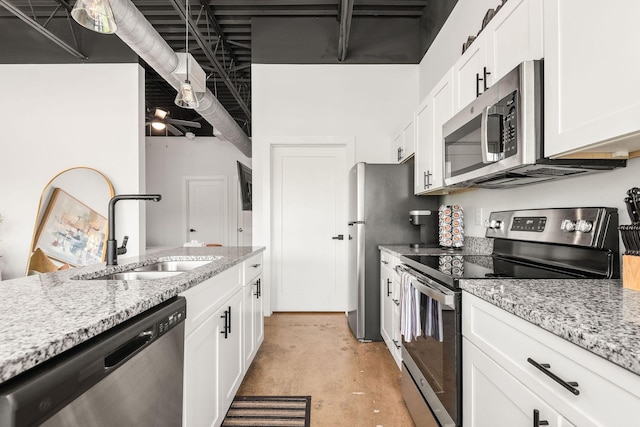 kitchen featuring stainless steel appliances, a sink, concrete floors, and white cabinets