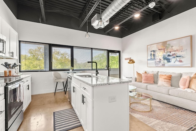 kitchen with appliances with stainless steel finishes, a sink, finished concrete flooring, open floor plan, and light stone counters