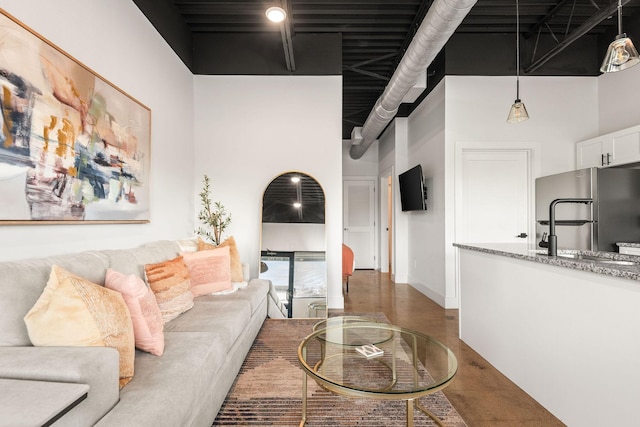 living area featuring a high ceiling, concrete floors, and baseboards