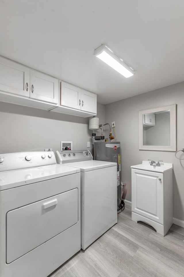 washroom featuring separate washer and dryer, electric water heater, light wood-type flooring, cabinet space, and baseboards