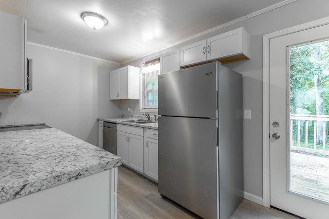 kitchen with stainless steel appliances, plenty of natural light, crown molding, and light wood finished floors