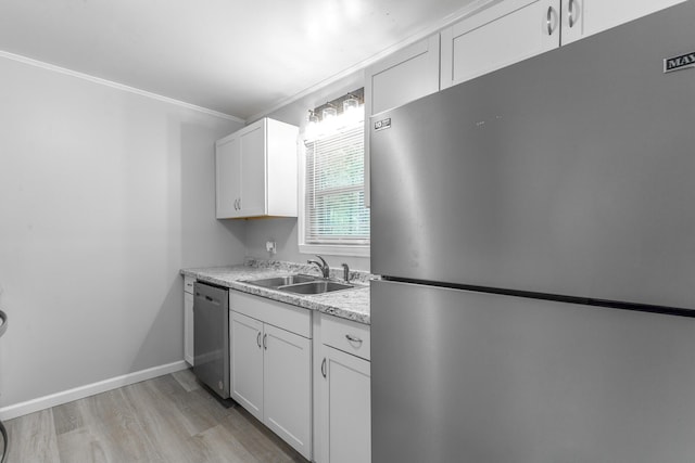 kitchen with appliances with stainless steel finishes, a sink, light wood-style floors, crown molding, and white cabinets