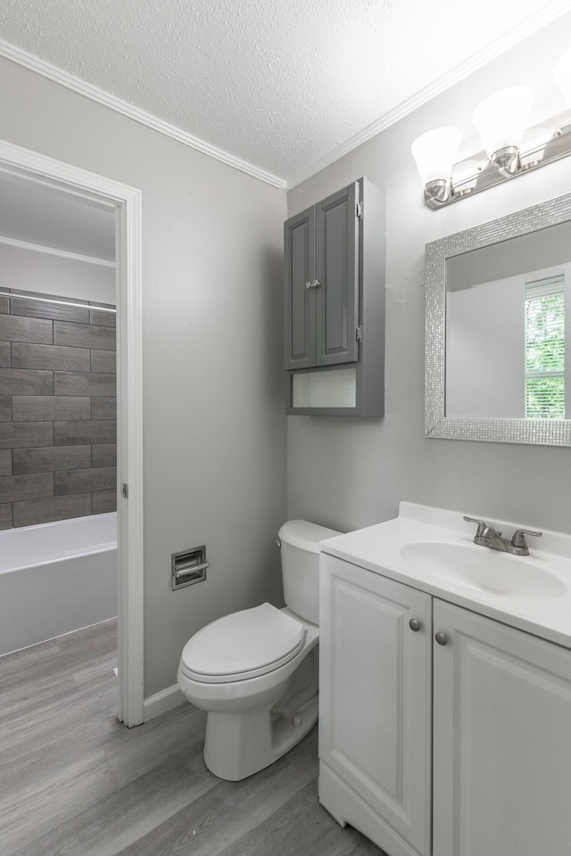 bathroom featuring toilet, wood finished floors, crown molding, vanity, and a textured ceiling