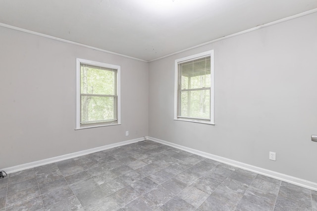 unfurnished room featuring plenty of natural light, crown molding, stone finish floors, and baseboards
