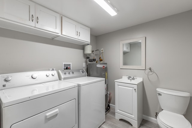 clothes washing area featuring washer and dryer, electric water heater, light wood finished floors, and baseboards