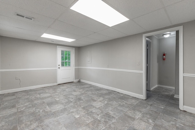 basement with baseboards, a drop ceiling, and stone finish flooring