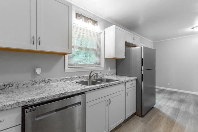 kitchen with stainless steel appliances, a sink, light wood-style flooring, white cabinets, and ornamental molding