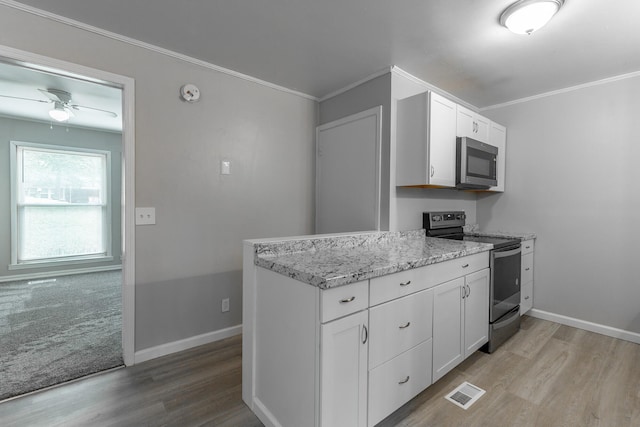 kitchen with appliances with stainless steel finishes, light wood finished floors, white cabinets, baseboards, and ornamental molding