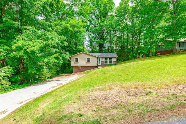 view of front of house featuring asphalt driveway, a front yard, and brick siding