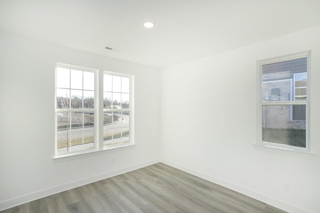 spare room with wood finished floors, baseboards, and recessed lighting