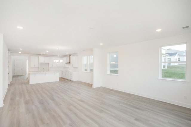 unfurnished living room with plenty of natural light, a chandelier, baseboards, and recessed lighting
