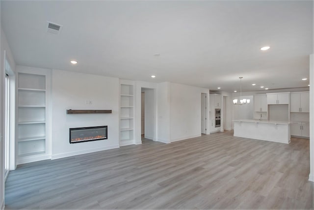 113 W Cassa Way, Mount Juliet, TN 37122 - unfurnished living room featuring built in features, a glass covered fireplace, recessed lighting, a chandelier, and baseboards