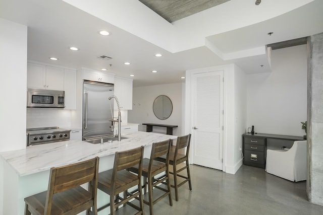 kitchen featuring appliances with stainless steel finishes, recessed lighting, tasteful backsplash, finished concrete floors, and white cabinetry